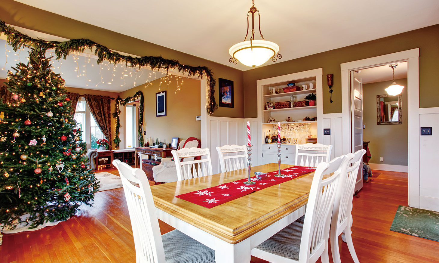 北欧の冬の過ごし方。日照時間が短い冬を明るいインテリアやクリスマスの飾りつけで楽しく過ごす北欧の家庭のダイニングルーム。大きなクリスマスツリーと温かな照明が印象的。