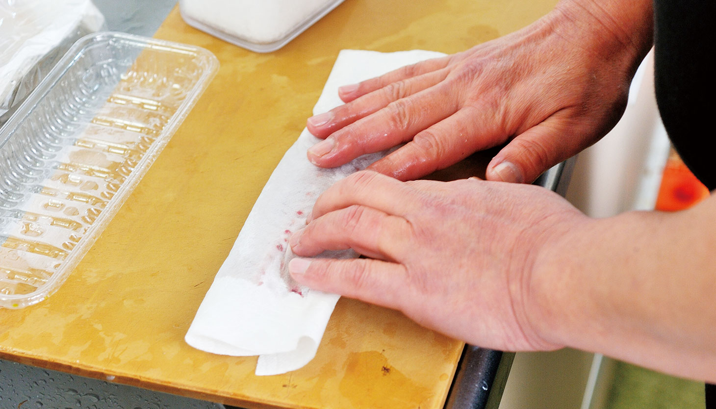 下処理した鯖をキッチンペーパーで包み、血や余分な水分を吸わせる工程