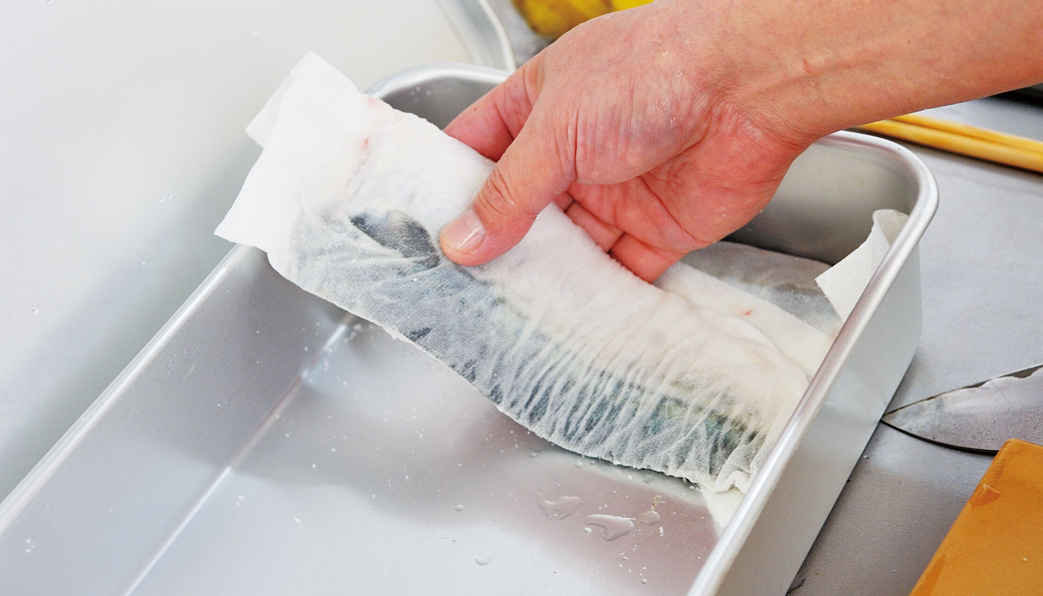 塩を当てた鯖をキッチンペーパーで包み保存容器に入れる工程
