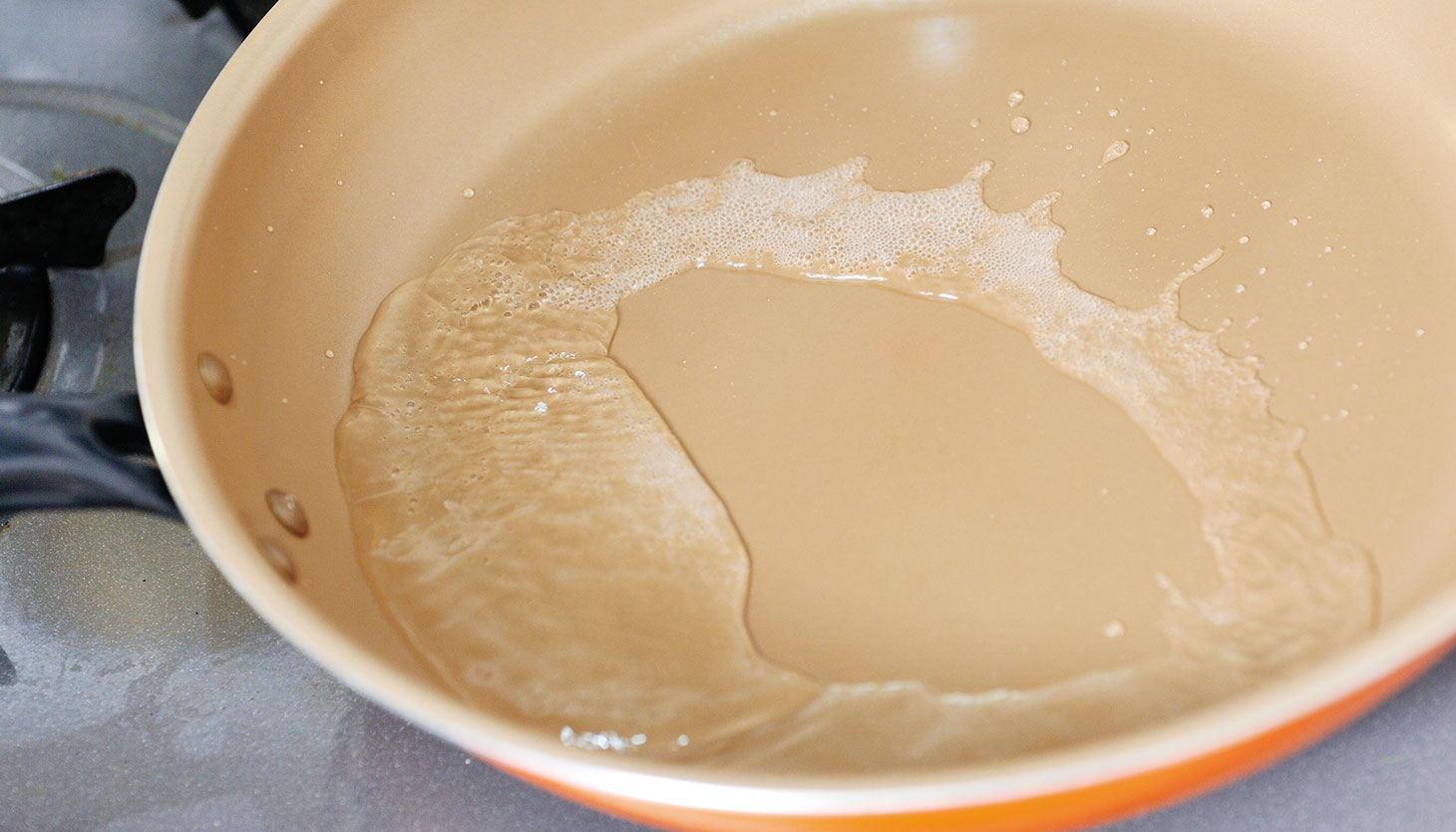 フライパンで酒を沸騰させ、カレイを煮る準備をしている様子