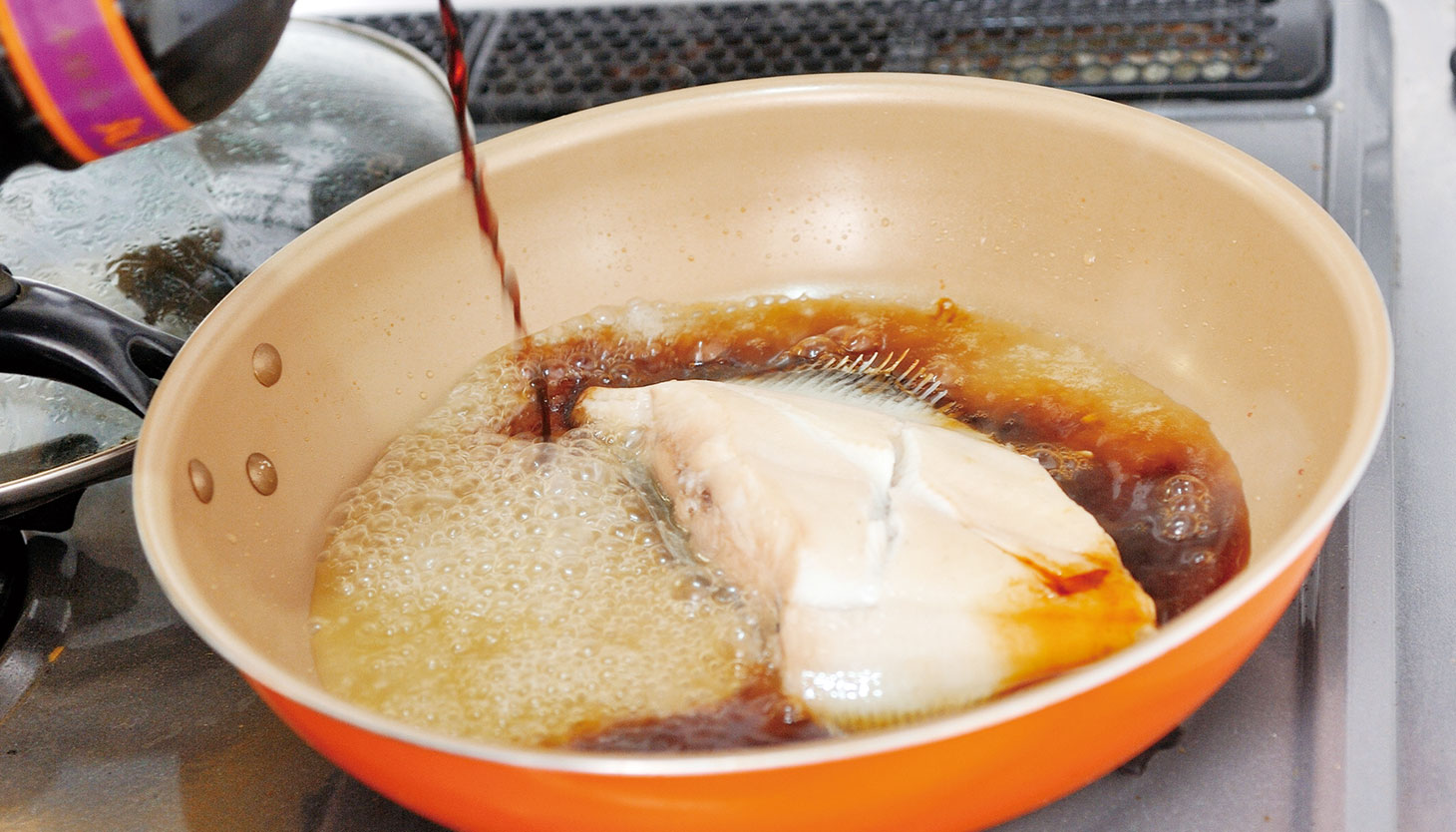 酒蒸ししたカレイに醤油を加えて煮付けている様子