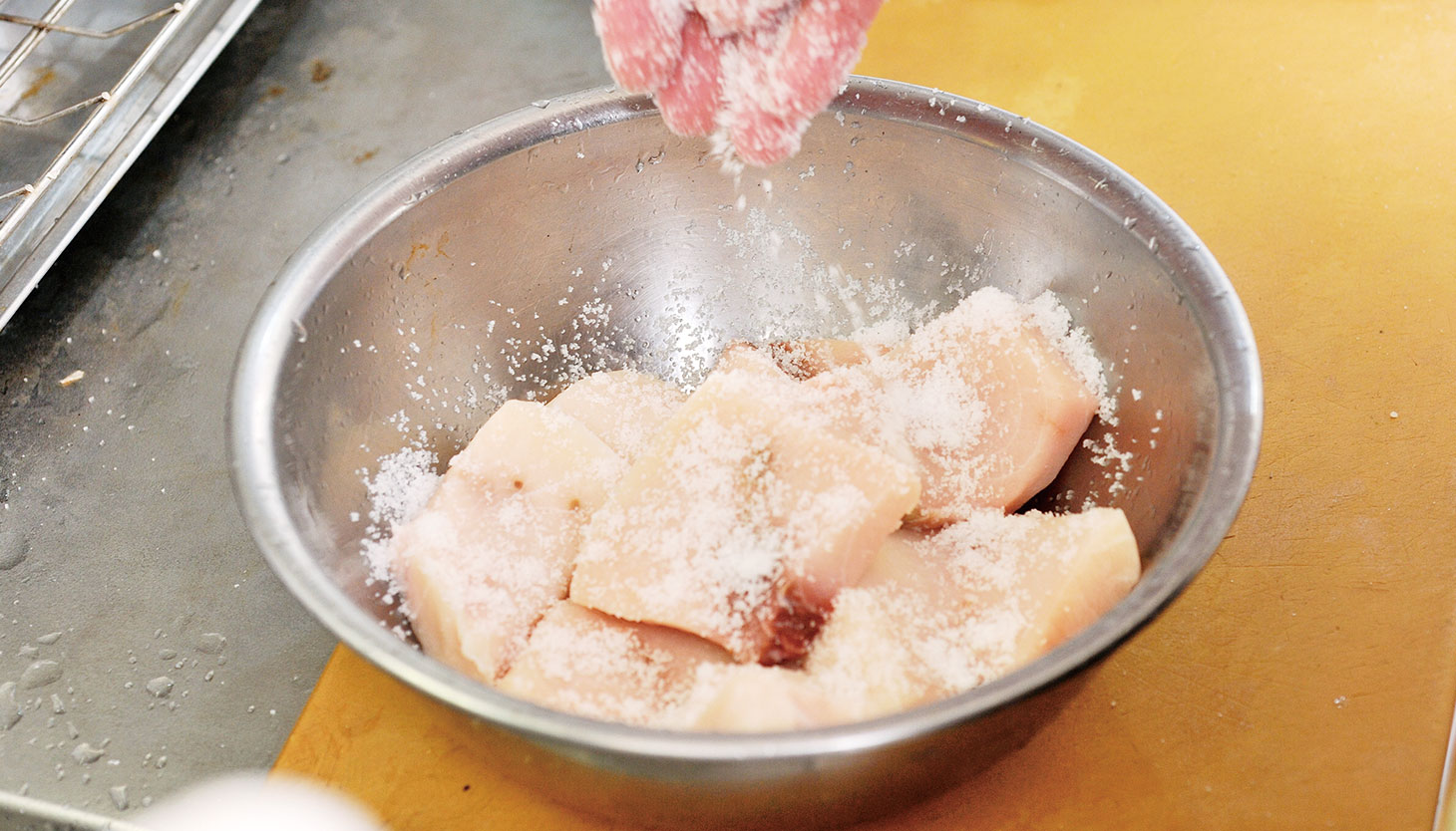 ボウルに入れた魚に塩を当てて下処理をする工程