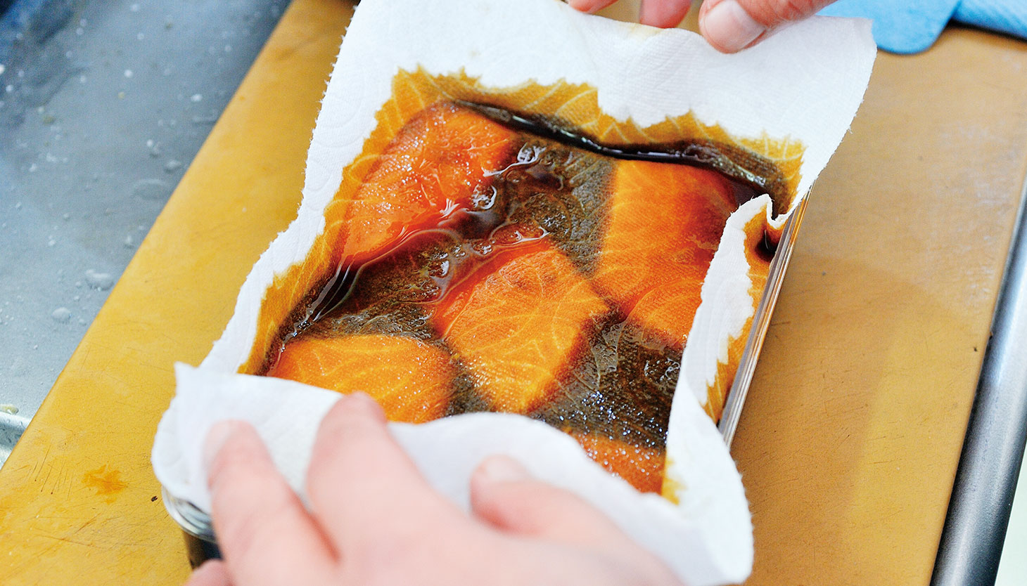 醤油漬けにした魚にキッチンペーパーをのせて保存する工程