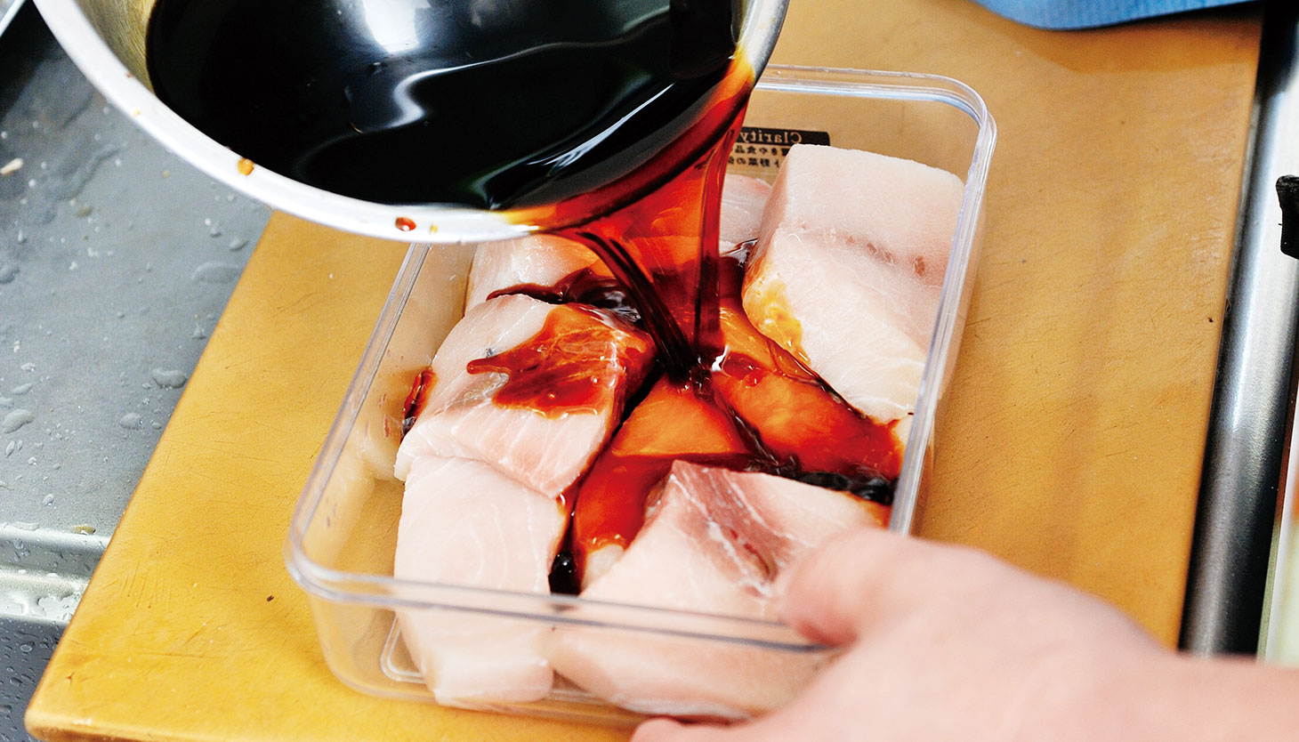 保存容器の魚に醤油だれを注いで漬ける工程