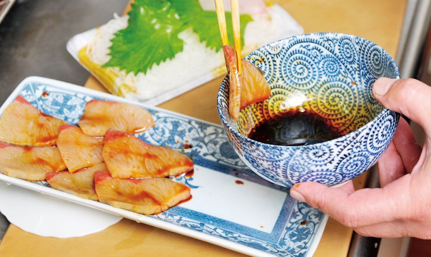 ボウルなどに醤油を入れ、その中で刺身を1枚ずつ洗う。シーン