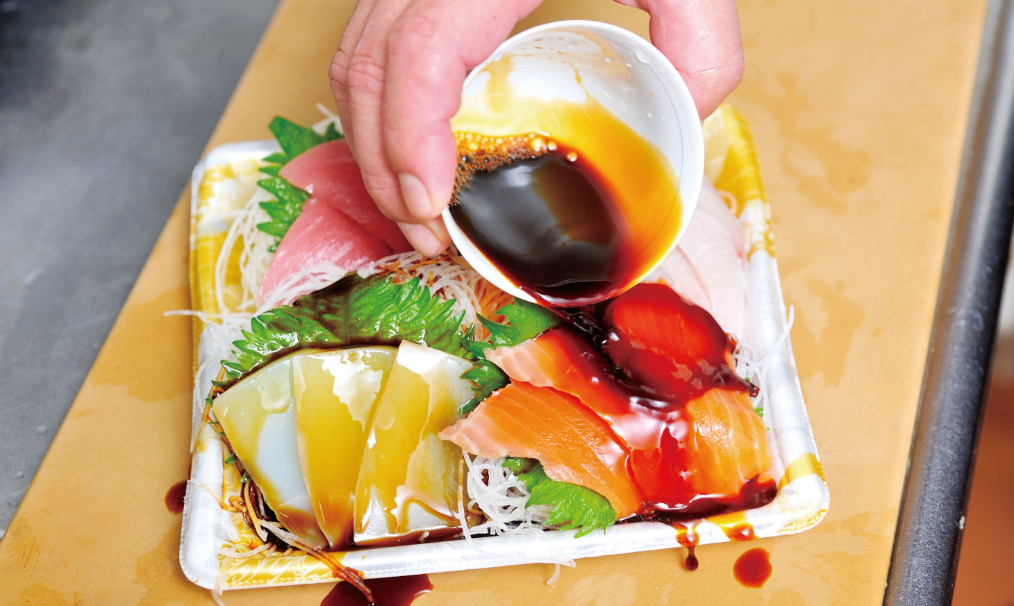 開いた刺身のパックにそのまま醤油を流しかけるシーン