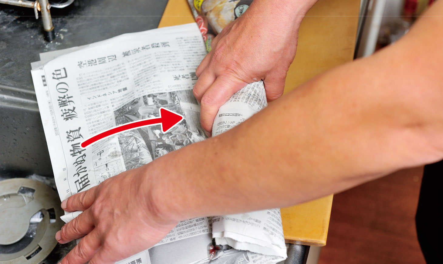 新聞の上に魚の骨や皮などのゴミを、包んでいくシーン